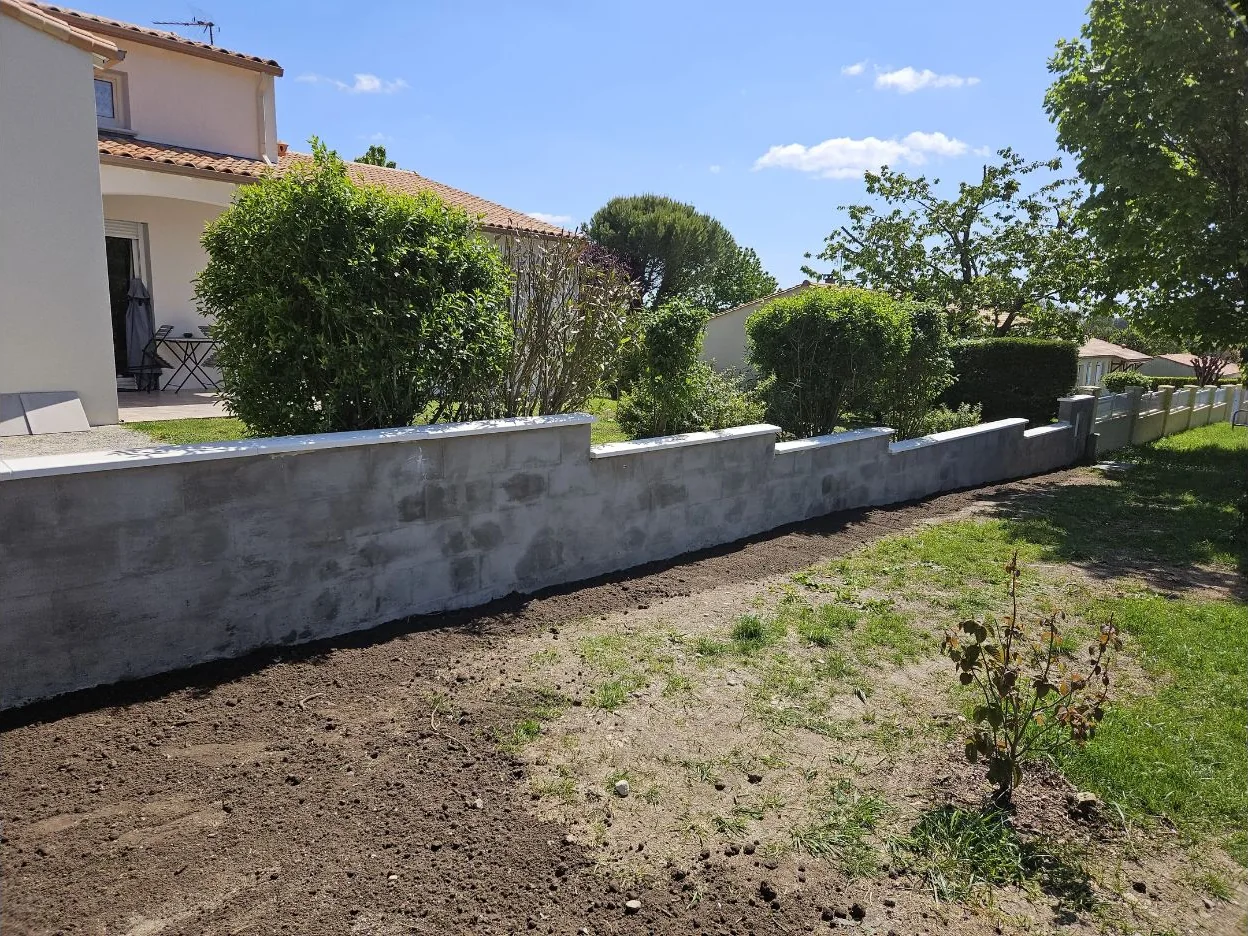 Muret de pierre et plantation au bord d’une allée